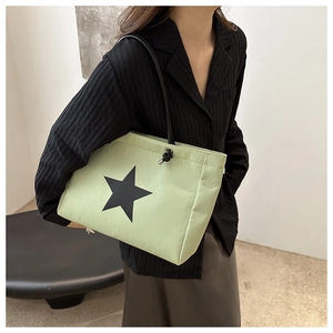 Detail of mint green puffer tote bag with black star pattern and nylon texture