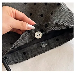 Close-up of magnetic metal clasp on grey herringbone fabric with black polka dots