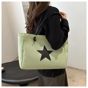Close-up of mint green tote bag featuring black star pattern and rope shoulder straps