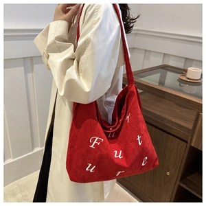 Detail of red corduroy tote bag with white Future embroidery held by a model