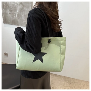 Detail of mint green nylon tote bag featuring a black star print and drawstring toggle
