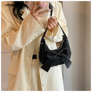 Close-up of black glossy hobo bag featuring a large bow detail and metallic zipper