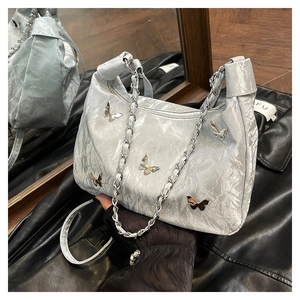 Close-up of metallic silver tote bag with butterfly charms and silver chain strap