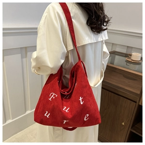 Detailed view of red corduroy tote bag with Future text embroidery worn by a model