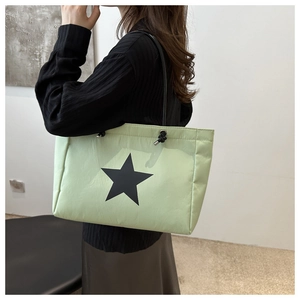 Detail view of light green tote bag with star pattern on a model for size perspective