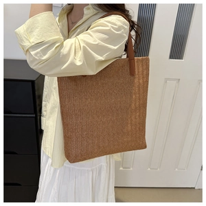 Grand sac cabas tressé marron avec anses en cuir porté par un mannequin féminin
