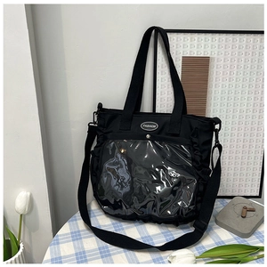 Detail of black nylon tote bag featuring a clear PVC pocket and adjustable strap