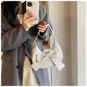Chic off-white half-moon bag with bow knot shown on model in stylish office outfit