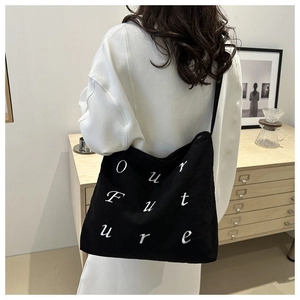 Detail of black corduroy shoulder bag featuring white Our Future letter embroidery