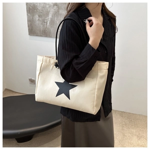 Detailed view of cream tote bag with black star print on a female shoulder