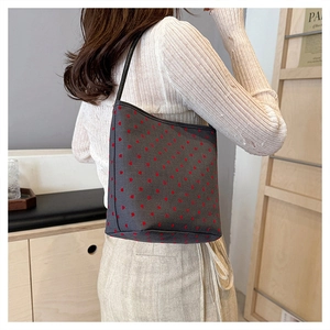 Detail view of charcoal grey shoulder bag with red heart patterns and black straps
