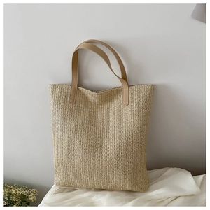Détail d'un sac cabas en paille tissée avec texture en V et anse en cuir marron