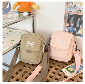 Detail of cute bow embroidery and nylon strap on small canvas crossbody bags