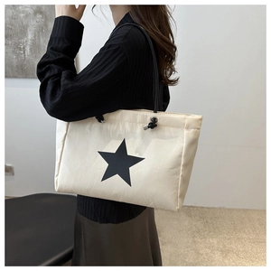 Detail of minimalist beige tote bag with black star print and functional drawstring