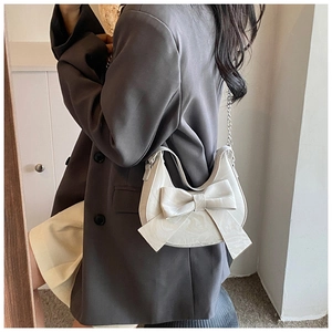 Chic cream bow shoulder bag with marble texture shown on a model in a minimalist room