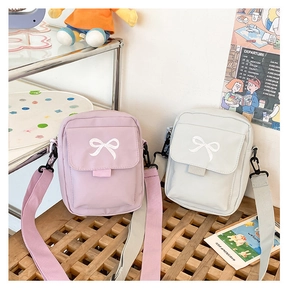 Detail of light purple and grey mini crossbody bags with embroidered bow and wide strap