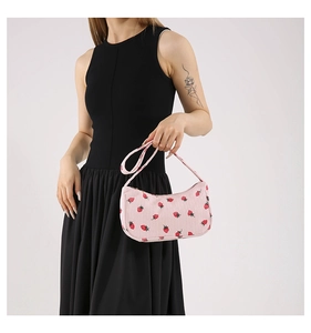 Détail du sac sous le bras en velours rose avec imprimé fraises rouges et fermeture éclair