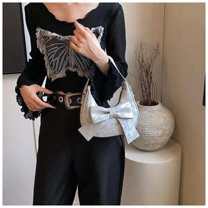 Detail of silver metallic hobo bag featuring a large decorative bow and marble texture
