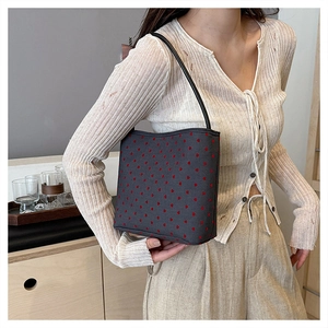 Detail of grey canvas shoulder bag with red heart pattern and slender straps