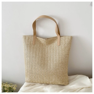 Détail de la texture tissée et de la poignée en similicuir d'un grand sac en paille