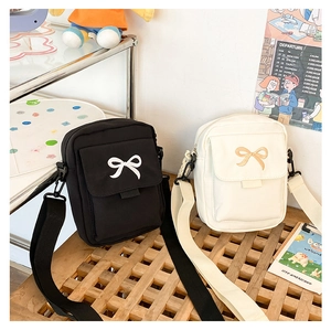 Detail view of black and cream canvas shoulder bags with cute bow embroidery for women