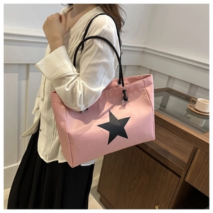 Lifestyle shot of a pink tote bag with a black star and cord strap worn by a model