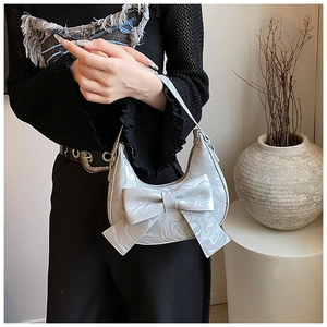 Detail of silver marble texture hobo bag with a large bow decoration and shoulder strap