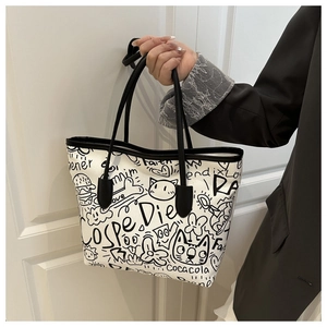 Detailed view of white canvas tote bag featuring black graffiti art and contrast handles