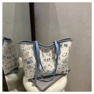 Detail of graffiti tote bag with light blue handles and playful cartoon prints