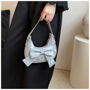 Detail of silver grey handbag featuring large 3D bow and marble texture finish