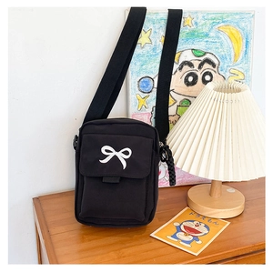 Close-up of black canvas bag with white bow embroidery and adjustable nylon strap