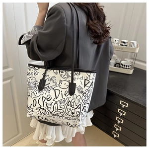 Detail of graffiti canvas tote bag with black leather straps and artistic prints