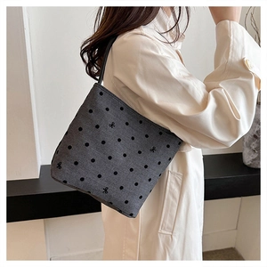 Detail of grey canvas tote bag featuring black polka dots and an embroidered bow