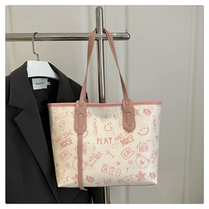 Detail of artistic graffiti patterns and pink shoulder strap on white tote bag