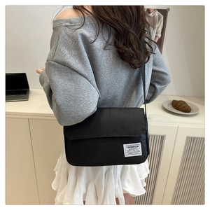 Detail view of the black Oxford cloth messenger bag styled with an urban casual outfit