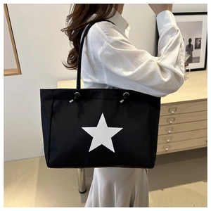 Detail of black nylon tote bag featuring a white star print and metal strap rings