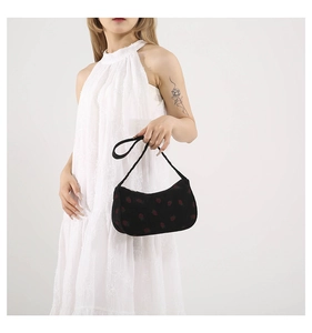 Mannequin portant un sac sous le bras en velours noir à motif fraise et robe blanche