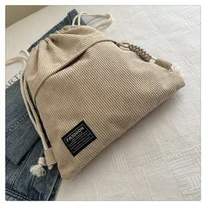Detail view of cream white corduroy drawstring backpack with black fashion label