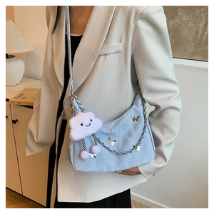 Detail of light blue tote bag with silver butterfly charms and chain strap carried by model