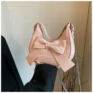 Detailed view of pink marble pattern handbag featuring a large decorative bow and silver chain