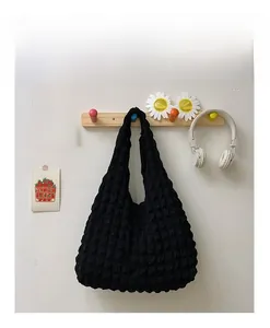 Detail showing the textured bubble knit fabric on a black shoulder tote bag