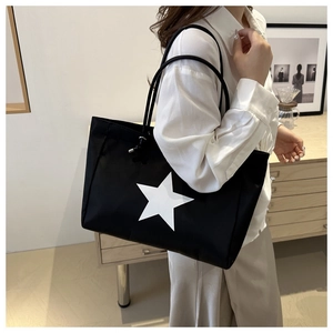 Detail of a casual black tote bag with a white star print, styled with a modern outfit