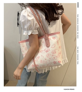 Detail of a white tote bag with pink trim and cute cartoon graffiti prints worn by a model