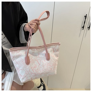 Detail view of the pink graffiti print and leather handles on the white canvas tote bag
