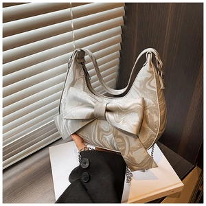 Detail view of marble patterned handbag with large bow and elegant metal chain strap