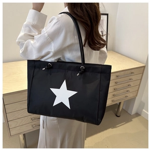 Close-up of black tote bag with white star pattern and decorative drawstring detail