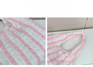 Close-up of pink and white seersucker fabric texture and handle detail on a tote bag