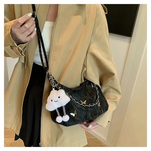 Detail of black pleated tote bag with silver chain, butterfly pendant and plush cloud charm