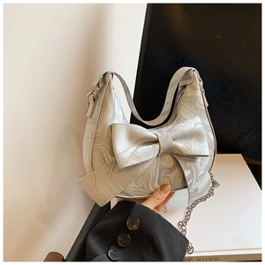 Detail of grey marble pattern handbag featuring a large bow and metallic chain strap