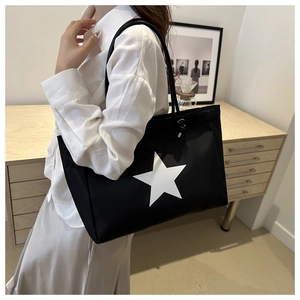 Detail of spacious black star tote bag showing large capacity and crossbody strap on model